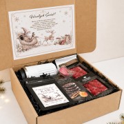 Otwarty box prezentowy z kubkiem termicznym, kawą, czekoladą i świąteczną wklejką.