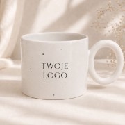 Biały ceramiczny kubek z miejscem na logo firmy w eleganckiej aranżacji.