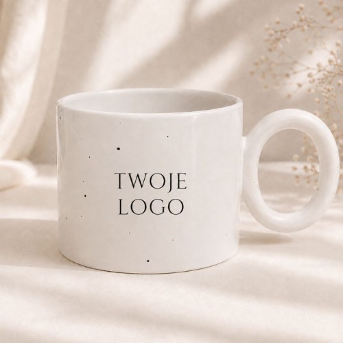 Biały ceramiczny kubek z miejscem na logo firmy w eleganckiej aranżacji.