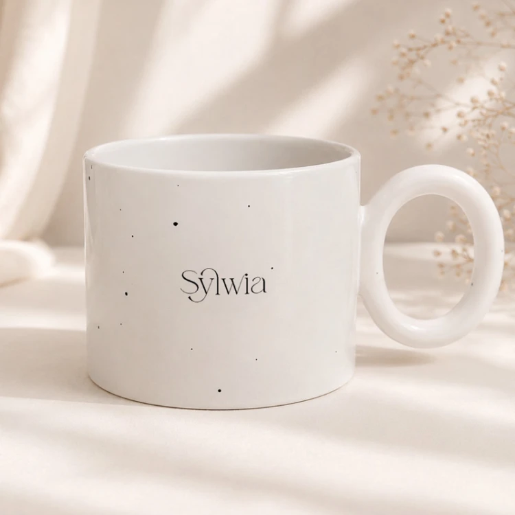 Biały ceramiczny kubek z delikatnym nakrapianym wzorem i personalizacją imieniem.