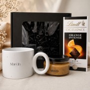 Elegancki zestaw prezentowy dla mężczyzny zawiera duży kubek z imieniem, miód oraz czekoladę Lindt.