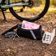Zestaw dla rowerzysty zawiera torbę na ramę, klucz wielofunkcyjny, łatki do opon oraz akcesoria pierwszej pomocy.