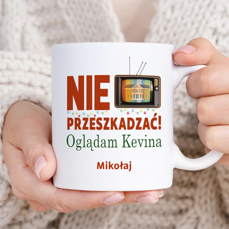 Biały kubek świąteczny z imieniem i grafiką telewizora to zabawny prezent dla miłośnika świątecznych filmów.
