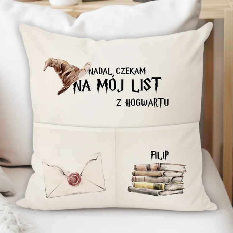 Poduszka z imieniem i magiczną grafiką przedstawiającą kapelusz, list oraz stos książek.