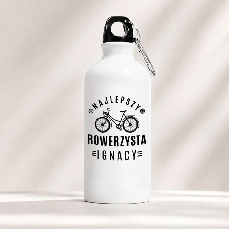 Biały bidon z napisem „Najlepszy Rowerzysta” i imieniem sprawdzi się jako prezent dla miłośnika dwóch kółek.