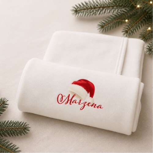 Personalizowany ręcznik kąpielowy z imieniem i świąteczną czapką Mikołaja na białym tle.