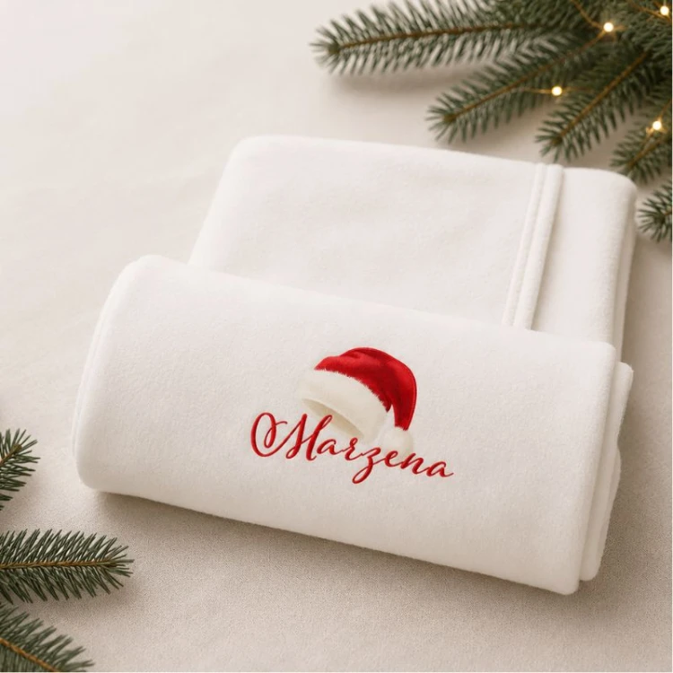 Personalizowany ręcznik kąpielowy z imieniem i świąteczną czapką Mikołaja na białym tle.