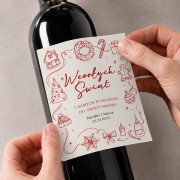 Personalizowana świąteczna etykieta na wino z czerwonymi ilustracjami i podpisem, naklejana na ciemną butelkę.