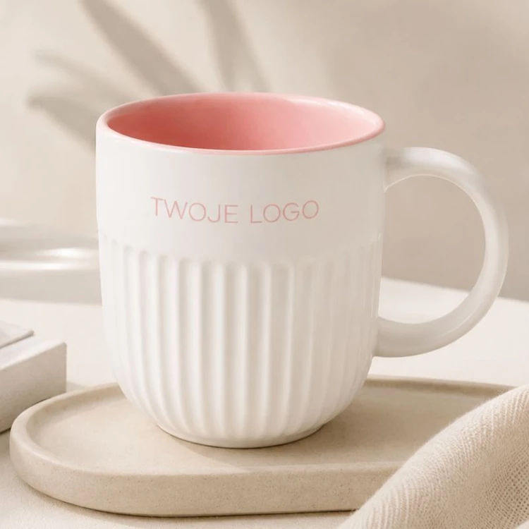 Ceramiczny kubek z ryflowaniem i różowym wnętrzem z logo firmy.